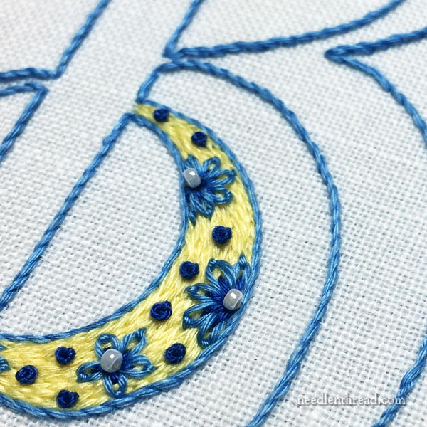Monogram in blue, yellow and white embroidery