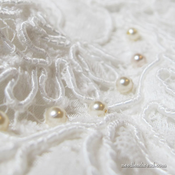 Hand beading a wedding gown with pearl beads